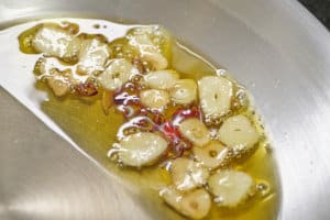 フライパンを傾けてニンニクを焼く