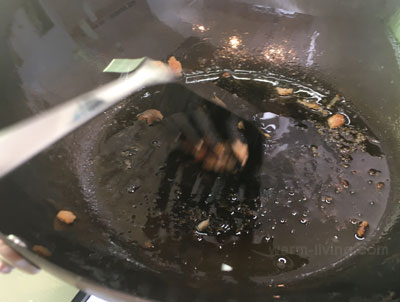 鍋底にくっついた肉を金属製ターナーでこすり落としている